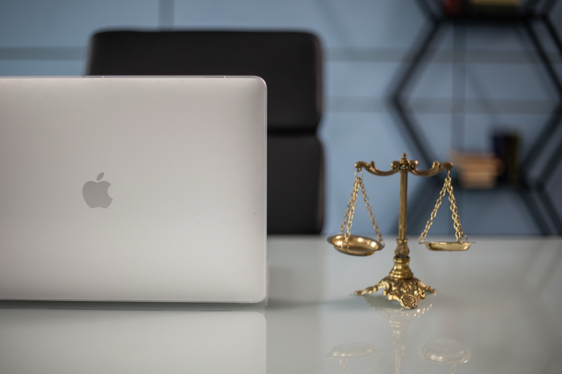 Brass scales of justice on a law office desk beside a laptop